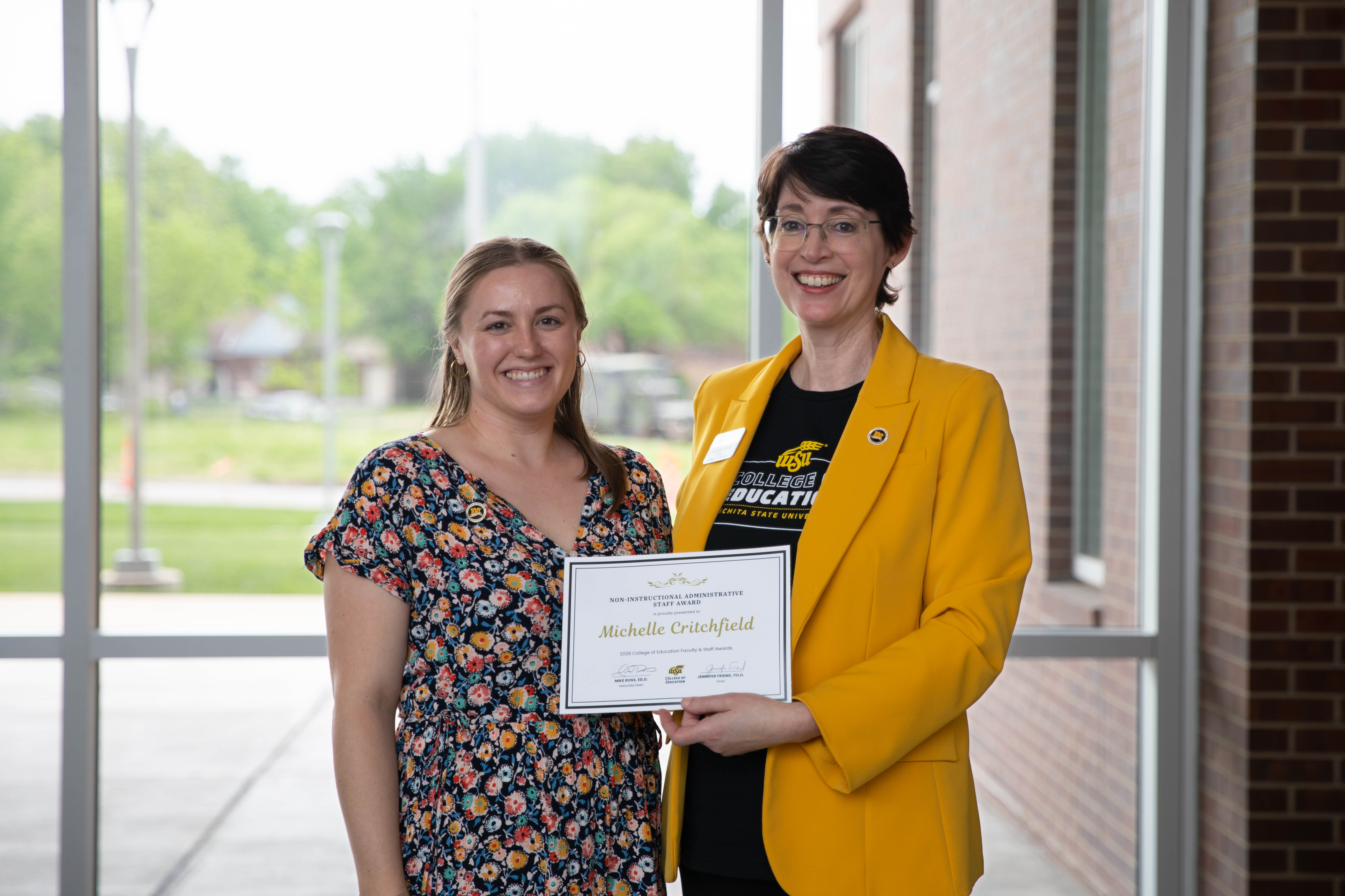 Michelle Critchfield holds an administrative staff award certificate while standing with Dr. Jennifer Friend, dean of the College of Education.