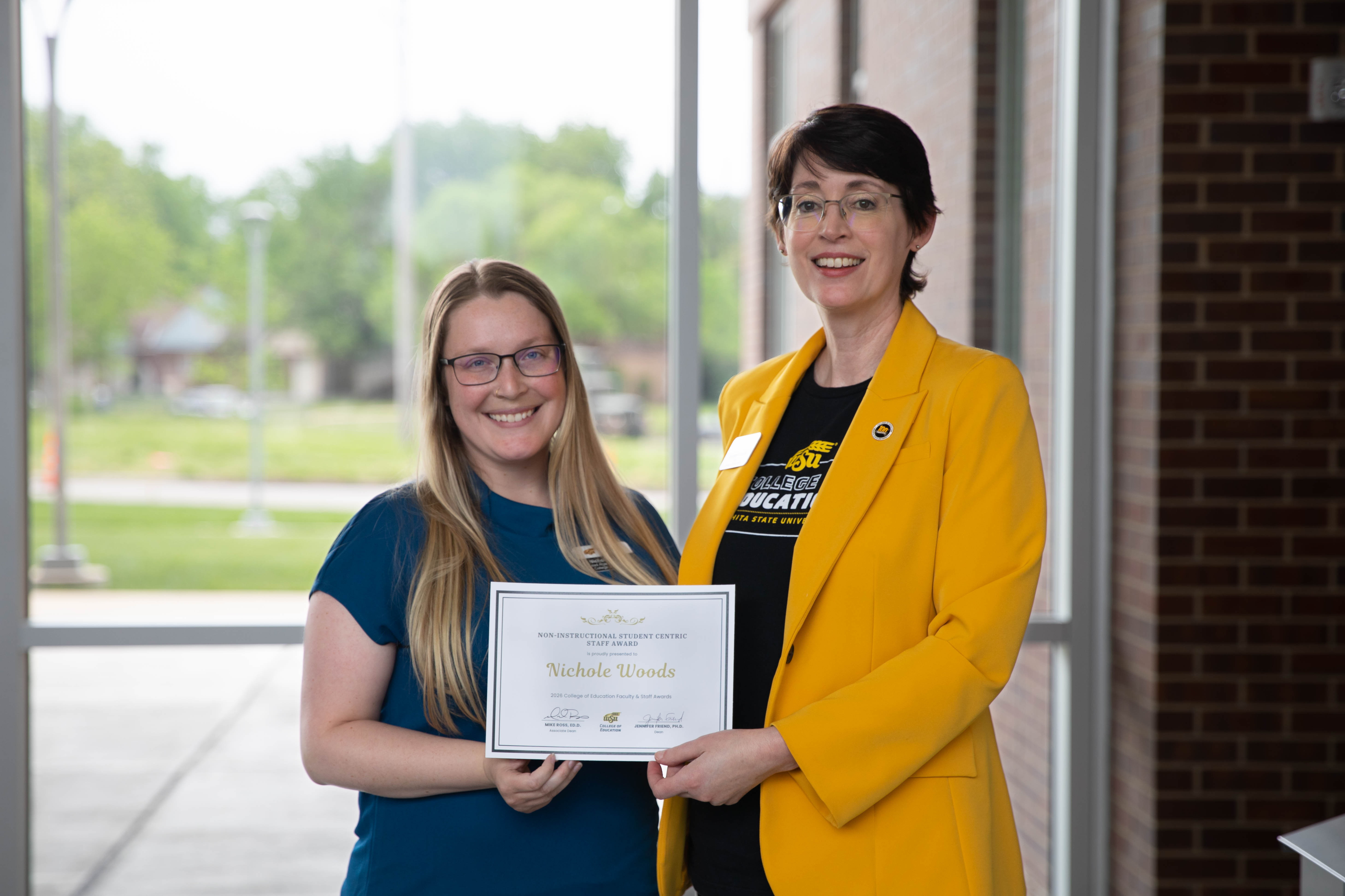 Nichole Woods holds a student-centric staff award certificate while posing with Dr. Jennifer Friend, dean of the College of Education.