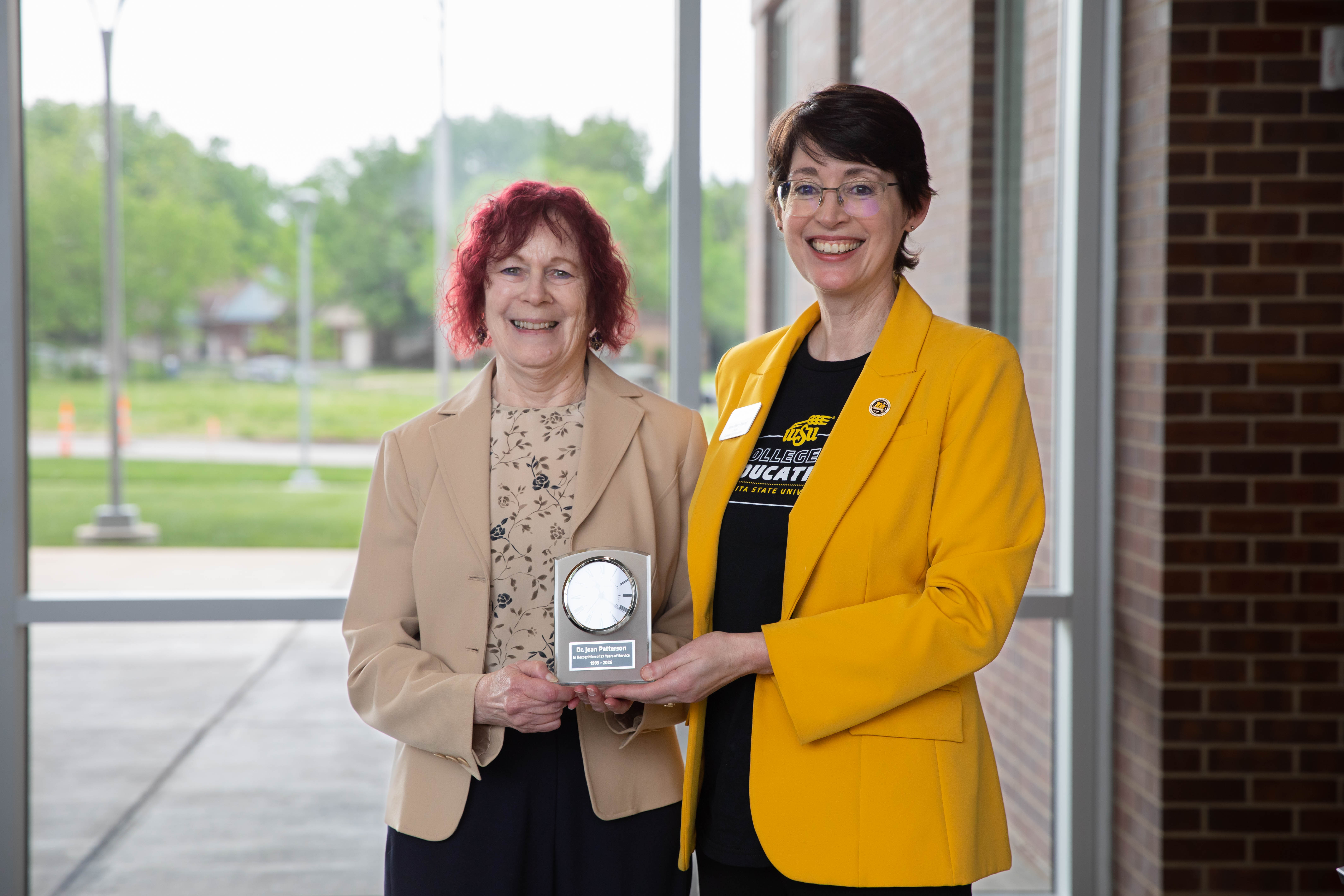 Dr. Jean Patterson holds a commemorative clock during her retirement recognition while standing with Dr. Jennifer Friend, dean of the College of Education.