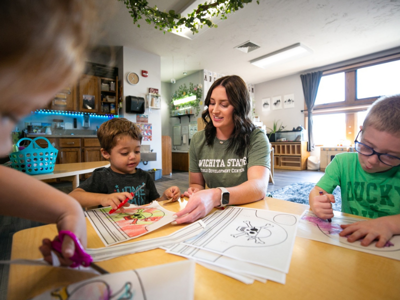 College of Education student, Ashlyn Riggs, sitting at a table teaching a student