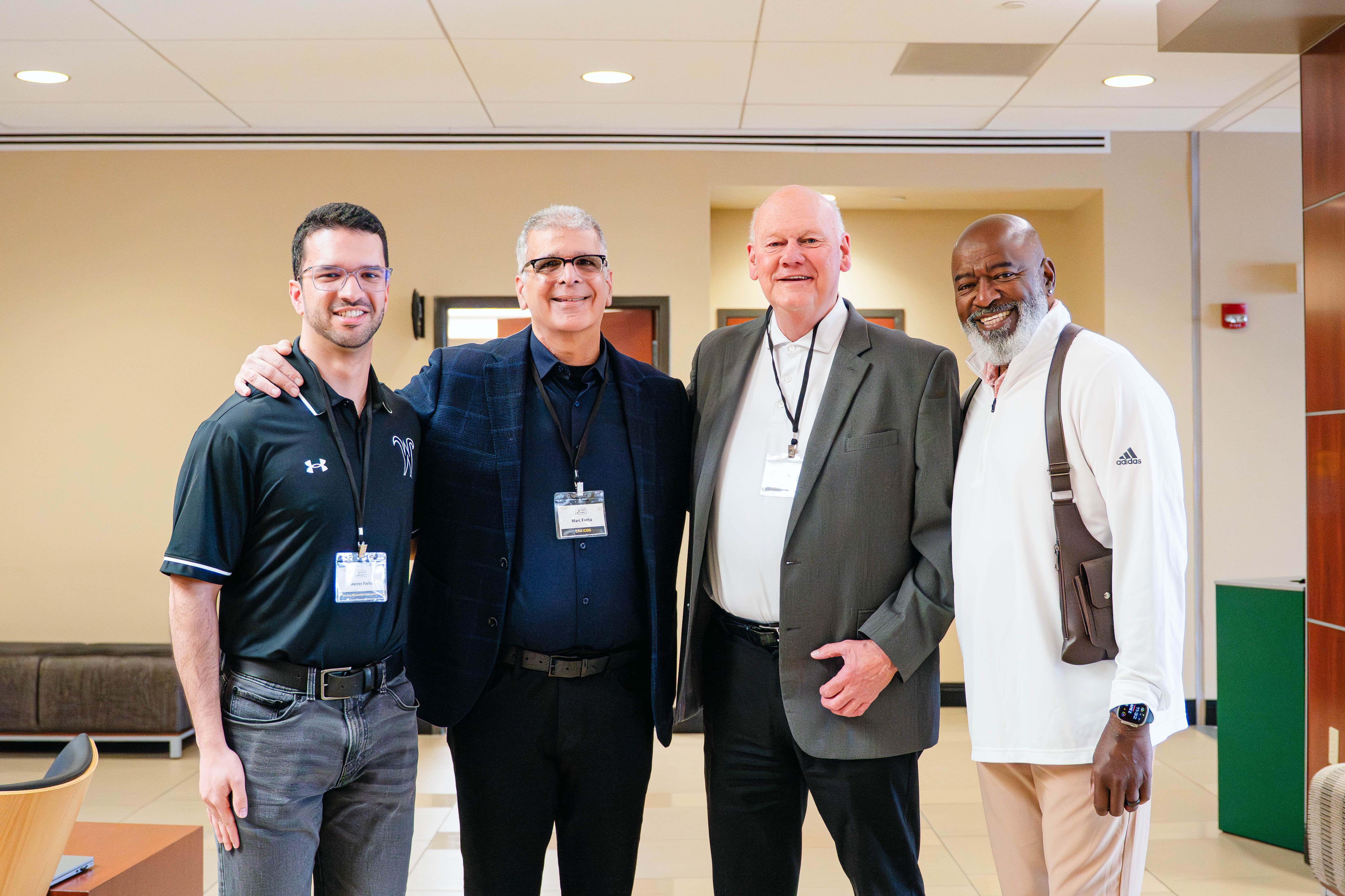 Four attendees pose together for a photo during the Kansas Sport Summit at Wichita State University in a lobby setting.