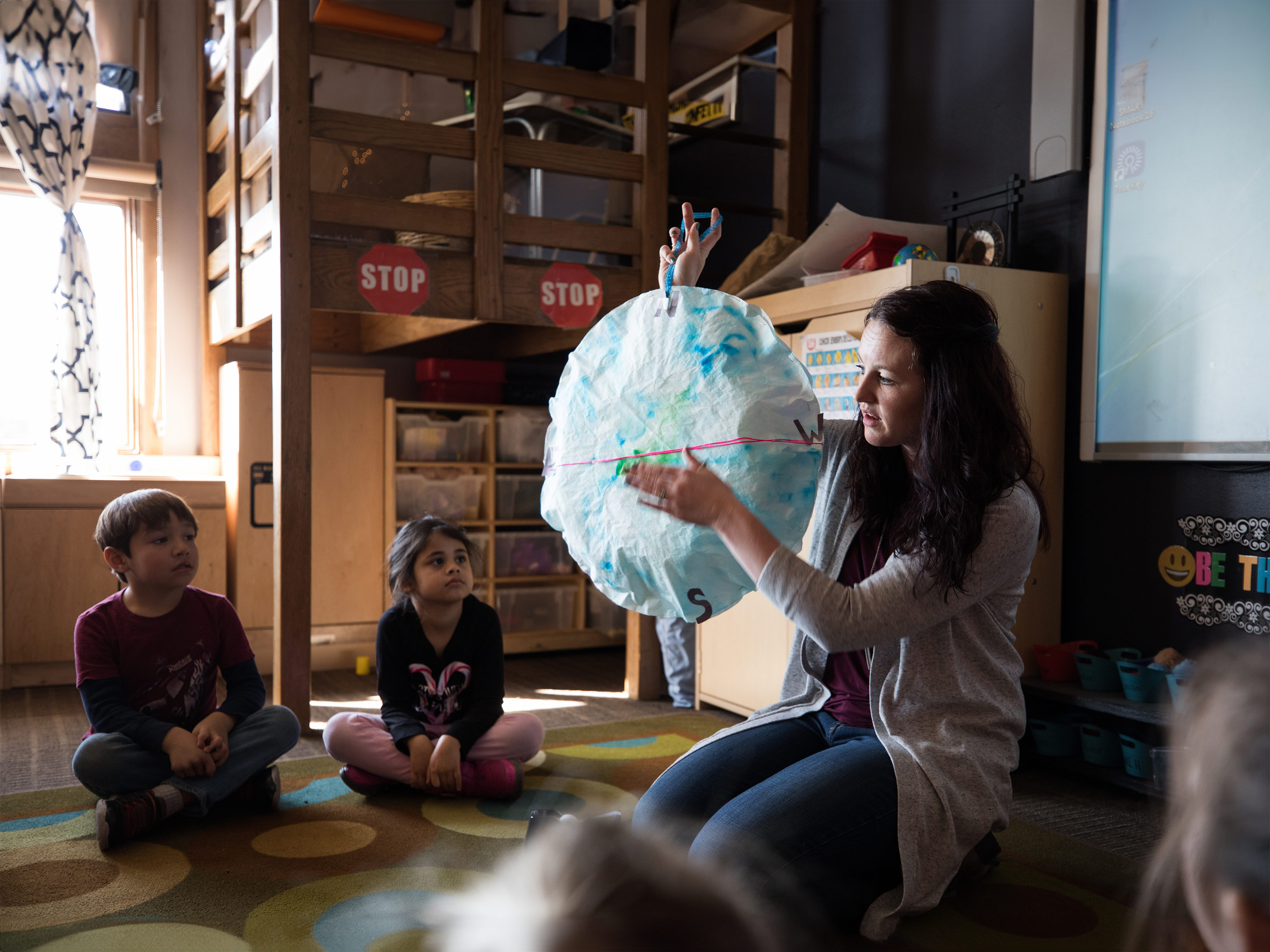 An educator demonstrates how to use a compass to students in the classrom 