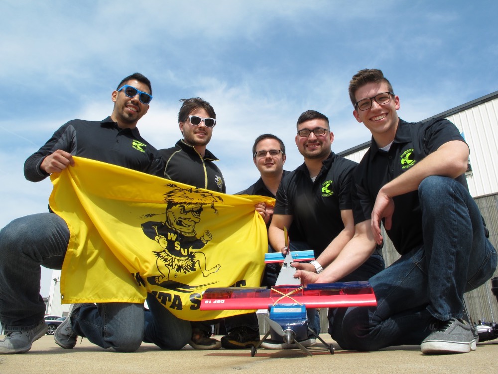 2018 DBF Team holding up a WuShock flag and showing their model airplane. 