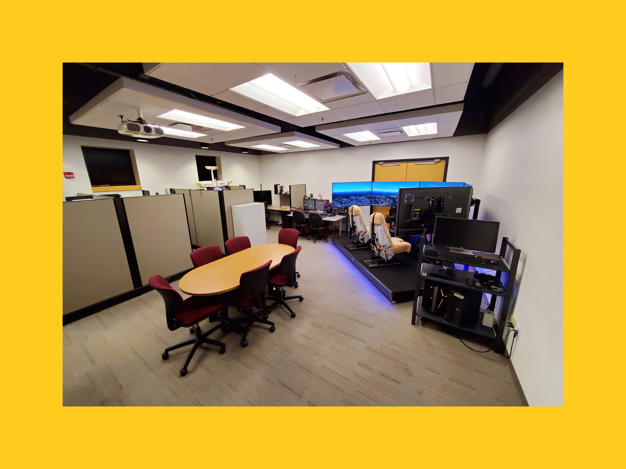 Photo of an area of the GAFL Lab that features the simulated cockpit and a meeting table with chairs. 