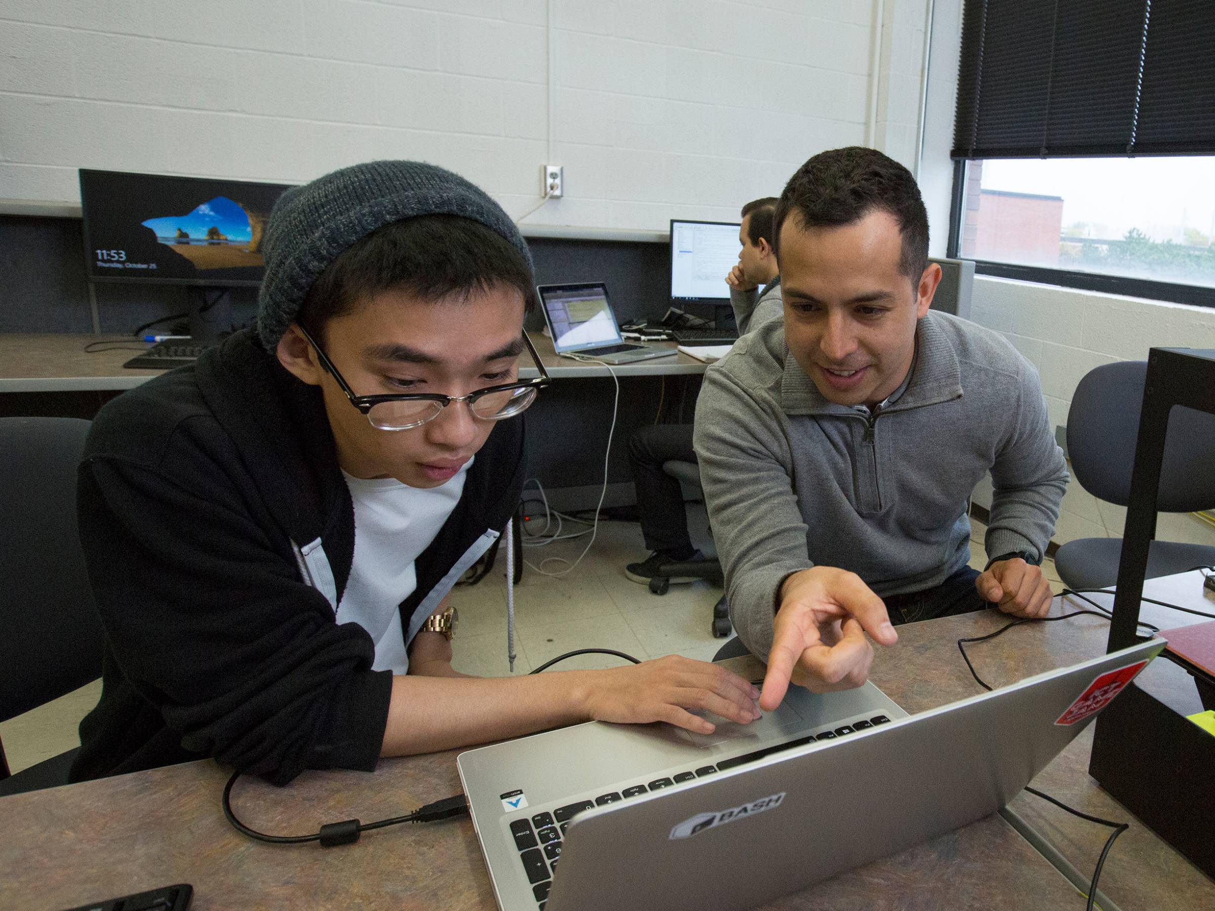 Two studentsm working in a lab in front of a laptop