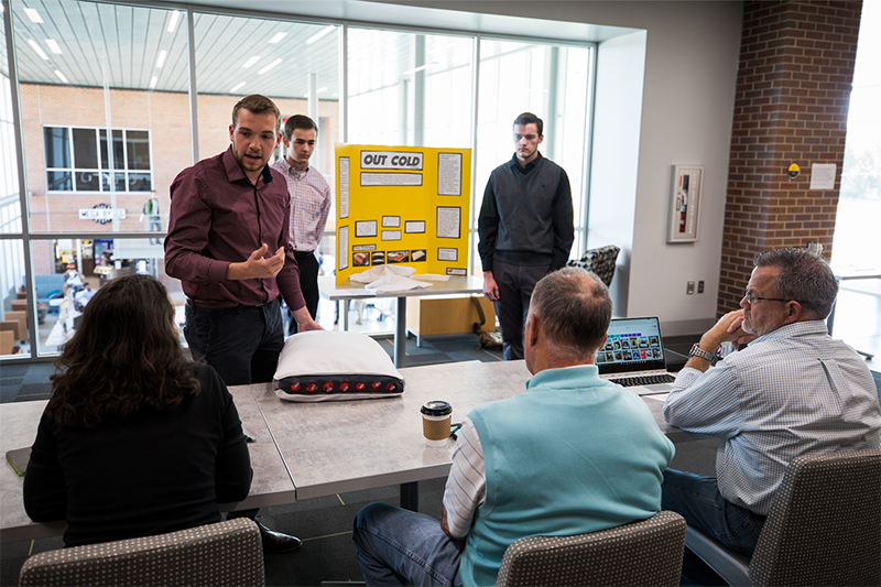 Students delivering an elevator pitch to a panel of judges.