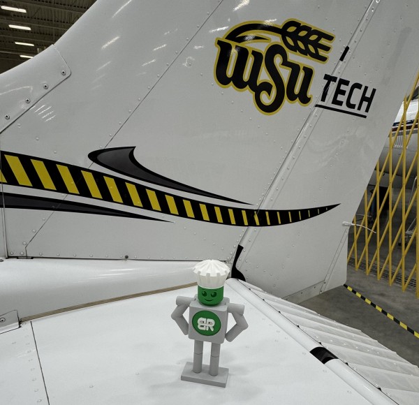 Manny (mascot) sitting on tail of a Cessna at WSU Tech