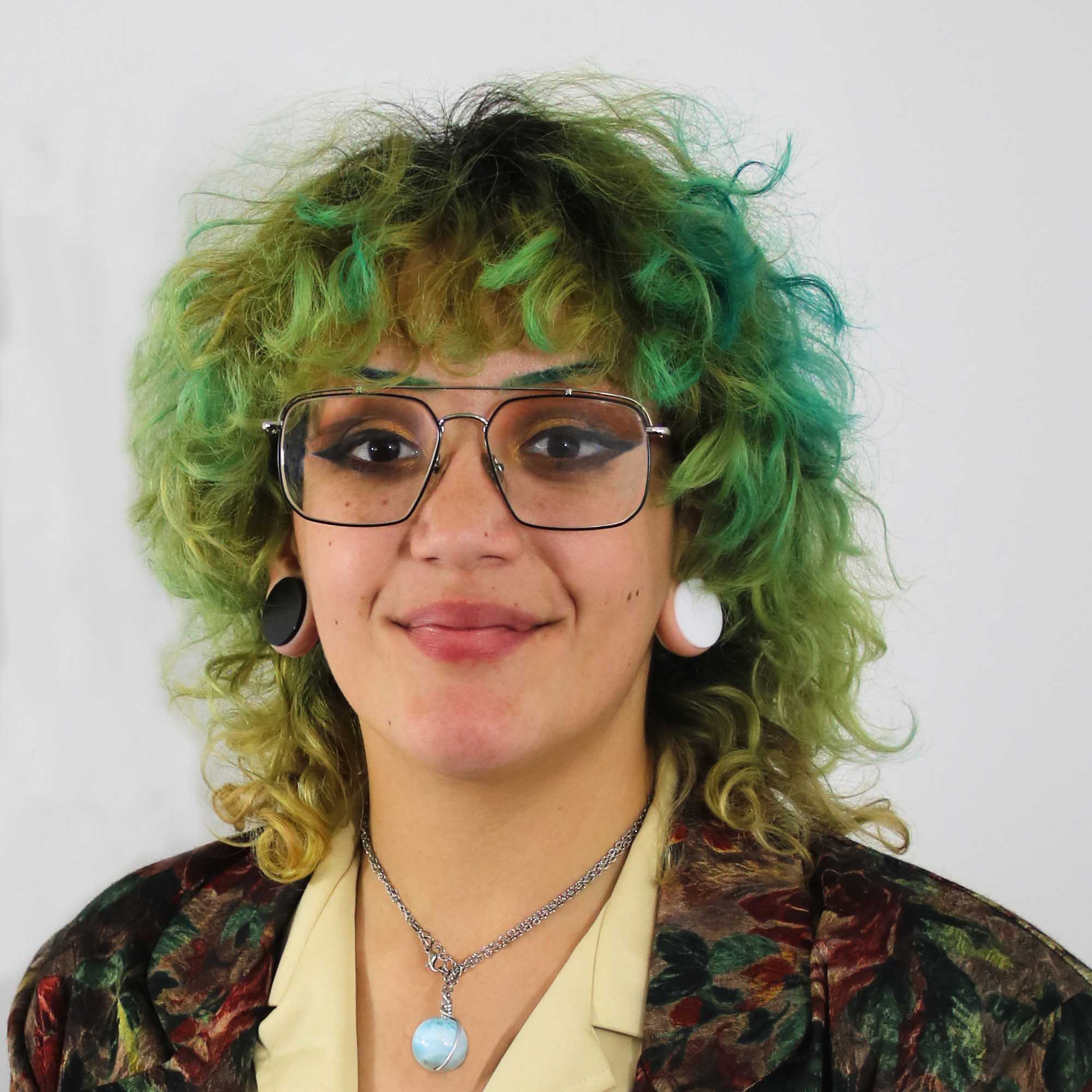 headshot of person with green hair and gauged ears