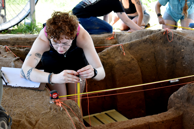 person with tattoos using line level and tape measure