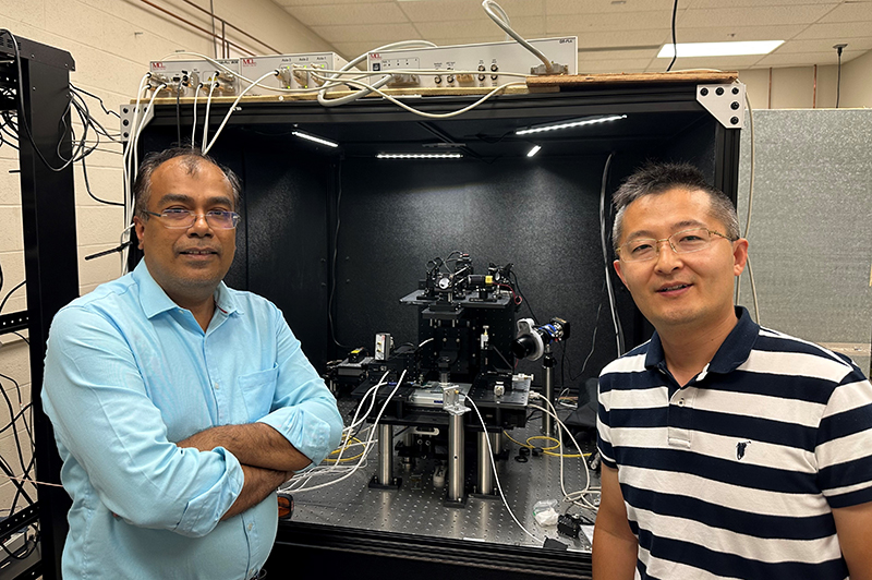Kapildeb Ambal and Jian Wang stand in front of the the single-spin quantum microscope they use to study quantum materials.