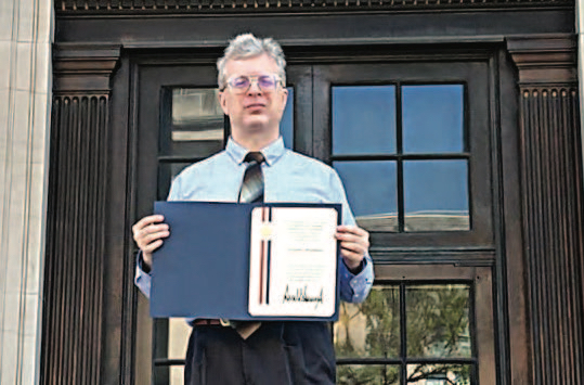 Photo: Alex Shvartsburg stands with his PECASE award in front of DAR Constitution Hall. 