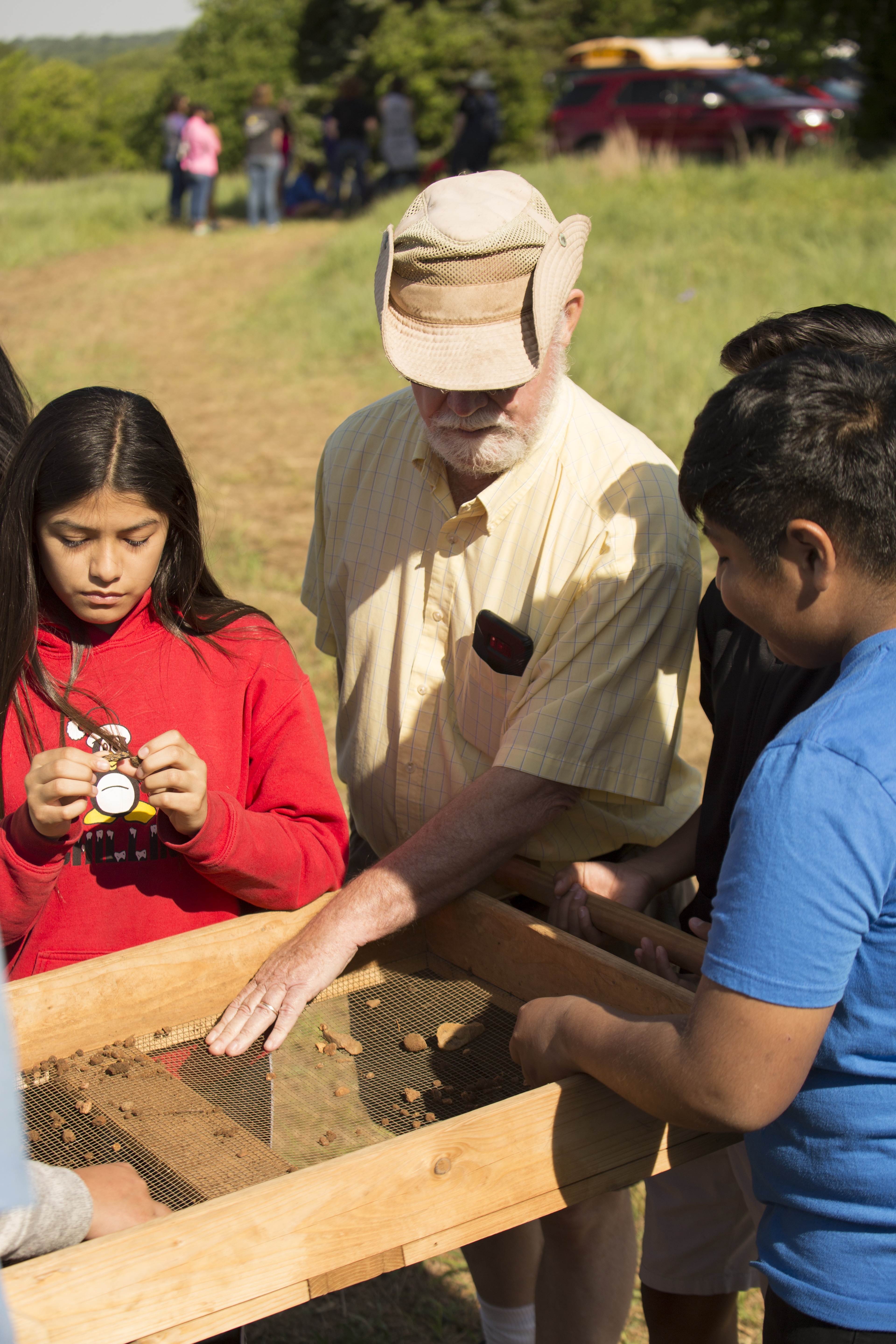 older white man at archaeology sifting screen with young girl
