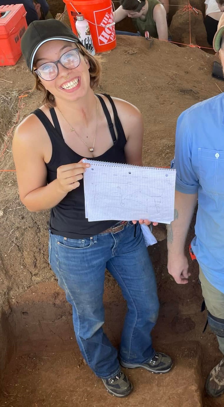 woman wearing glasses and baseball hat holding paper