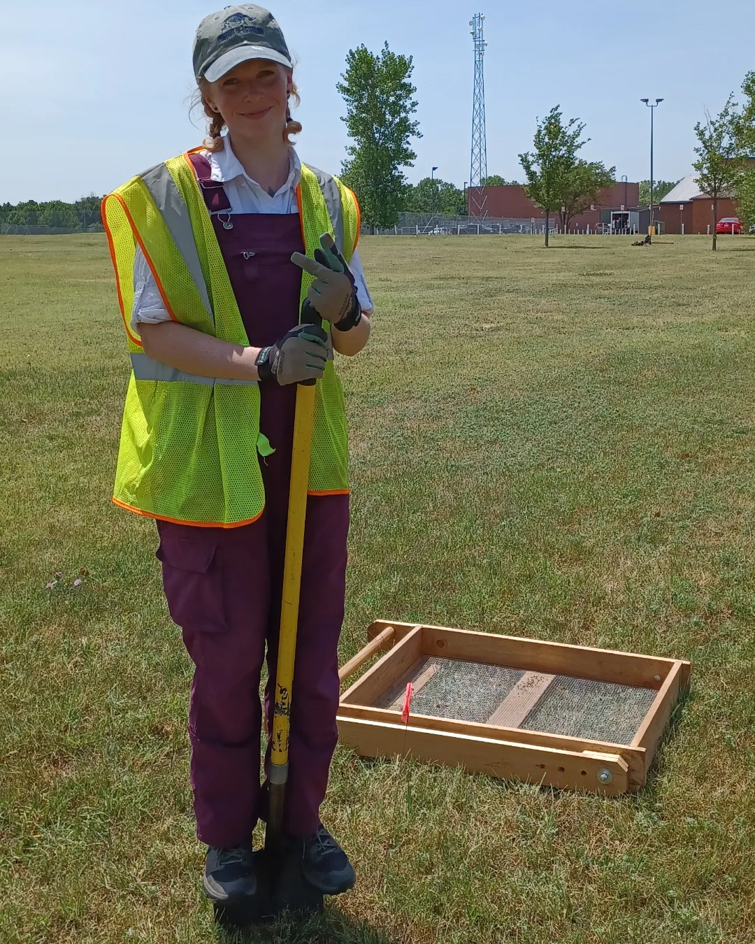 Woman in safety vest standing on shovel