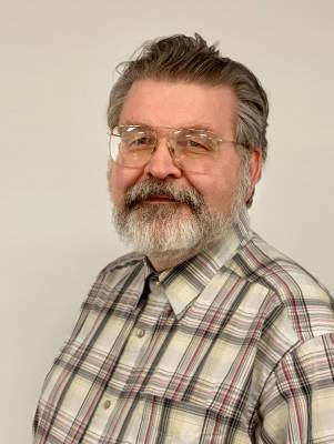 headshot of older white man with white beard smiling