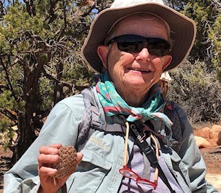 older white woman wearing hiking gear holding a pottery sherd