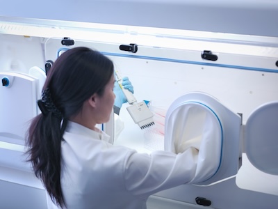 Microbiologist using pipette in BSL4 safety cabinet