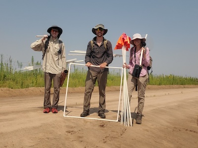 Student standing on dirt road with ecological research tools
