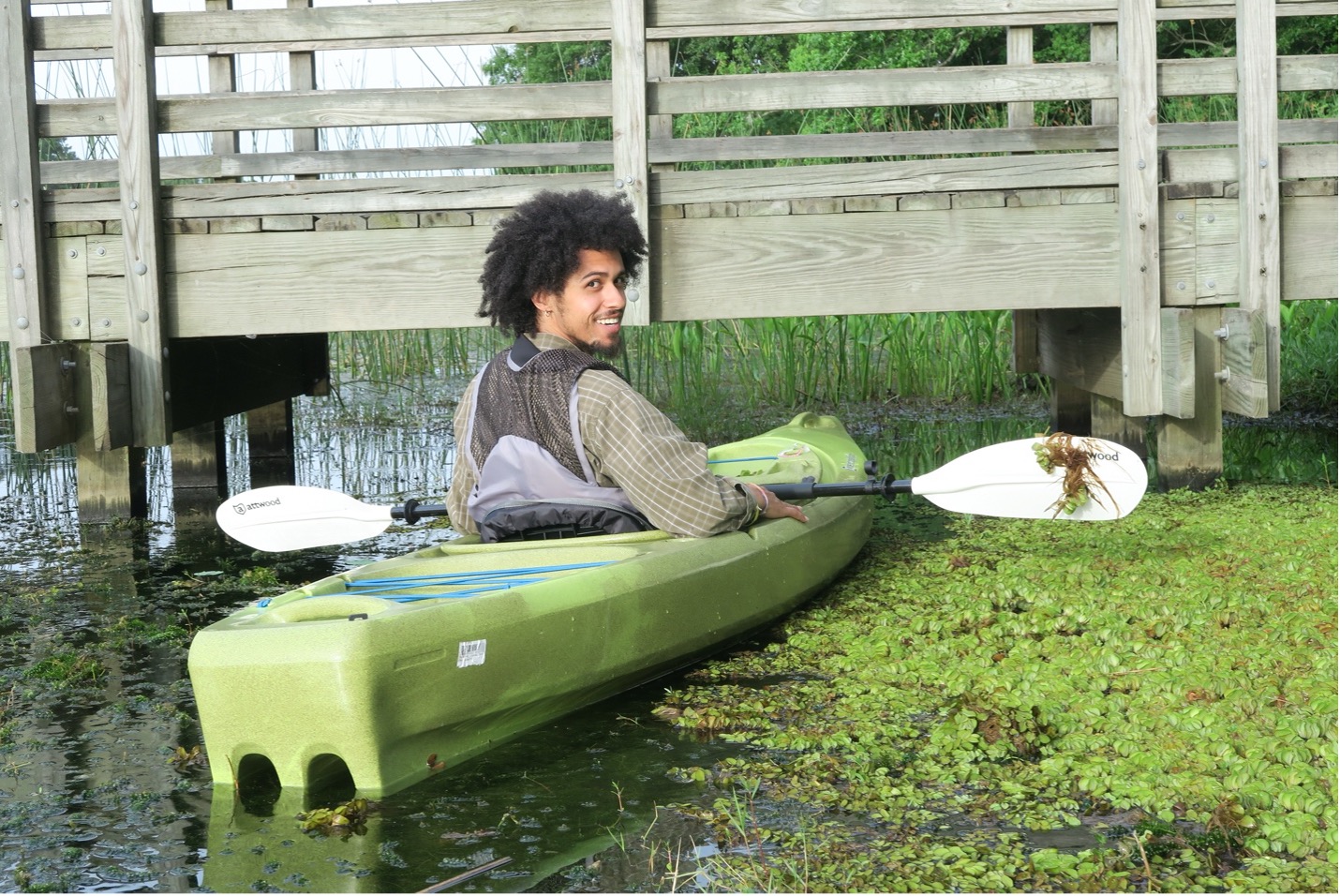 Student riding in a kayak, smiling over his shoulder