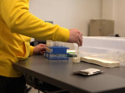 Student uses pipette to move heavy cream from a beaker to test tubes for an experiment.