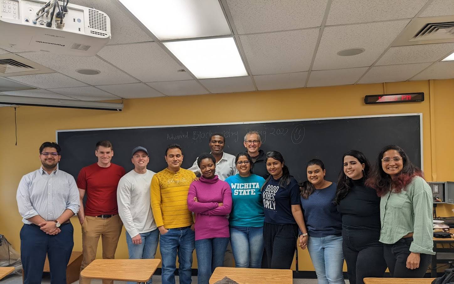Gradudate students and Prof. Jim Bann posing for a picture in front of a blackboard