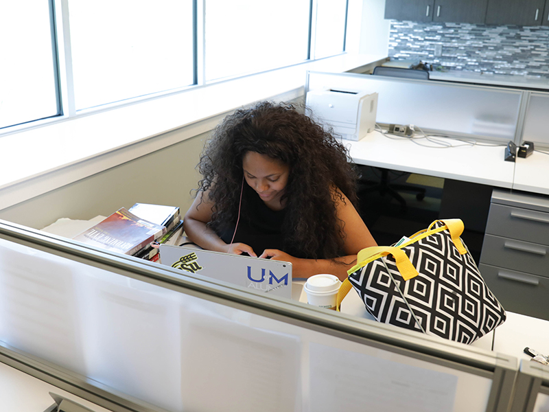 A student studies at a desk in an office area.