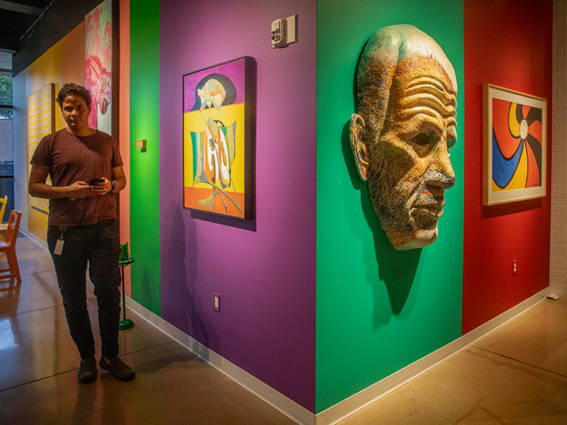 A student poses by a colorful wall featuring artwork