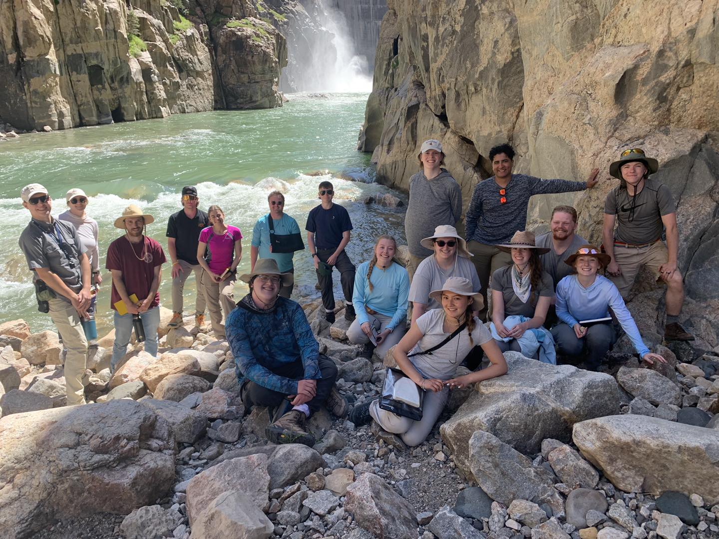 Geology students pose for a group picture in front of a riverbed