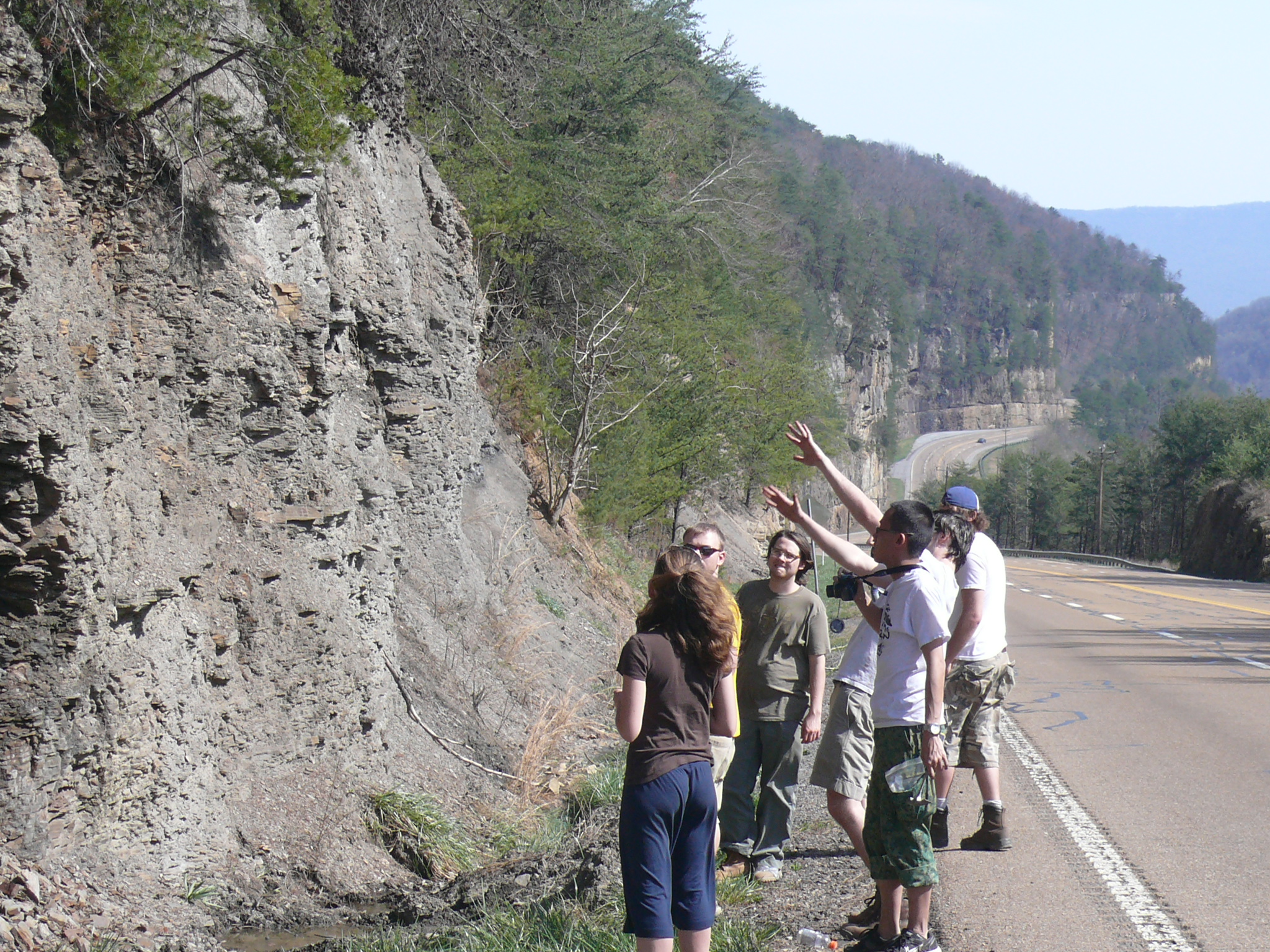 Students stop by the side of the road to examine rock