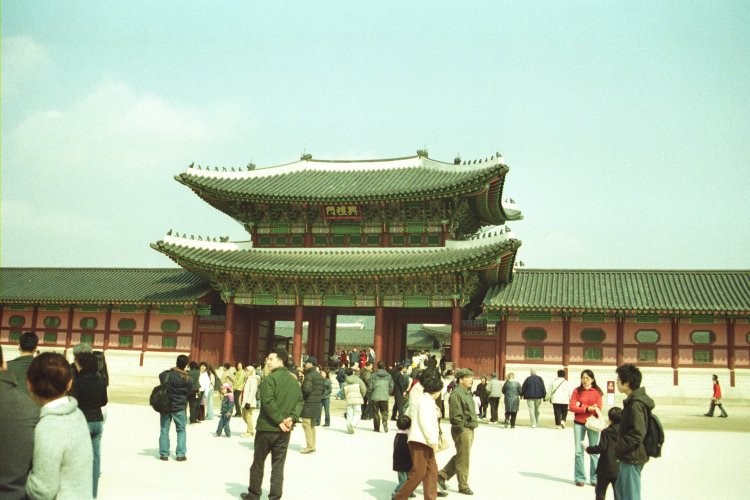 Photo of people walking in front of a Korean palace gate. 
