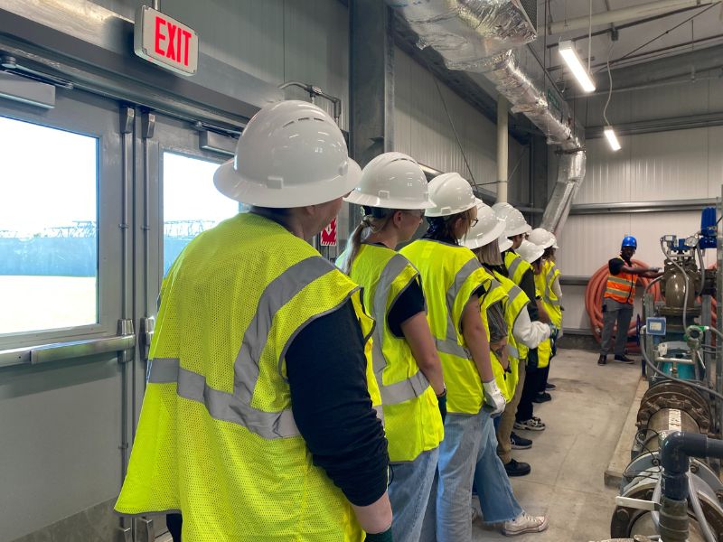 students with hard hats and safety vests lined up during a tour of a water treatment facility