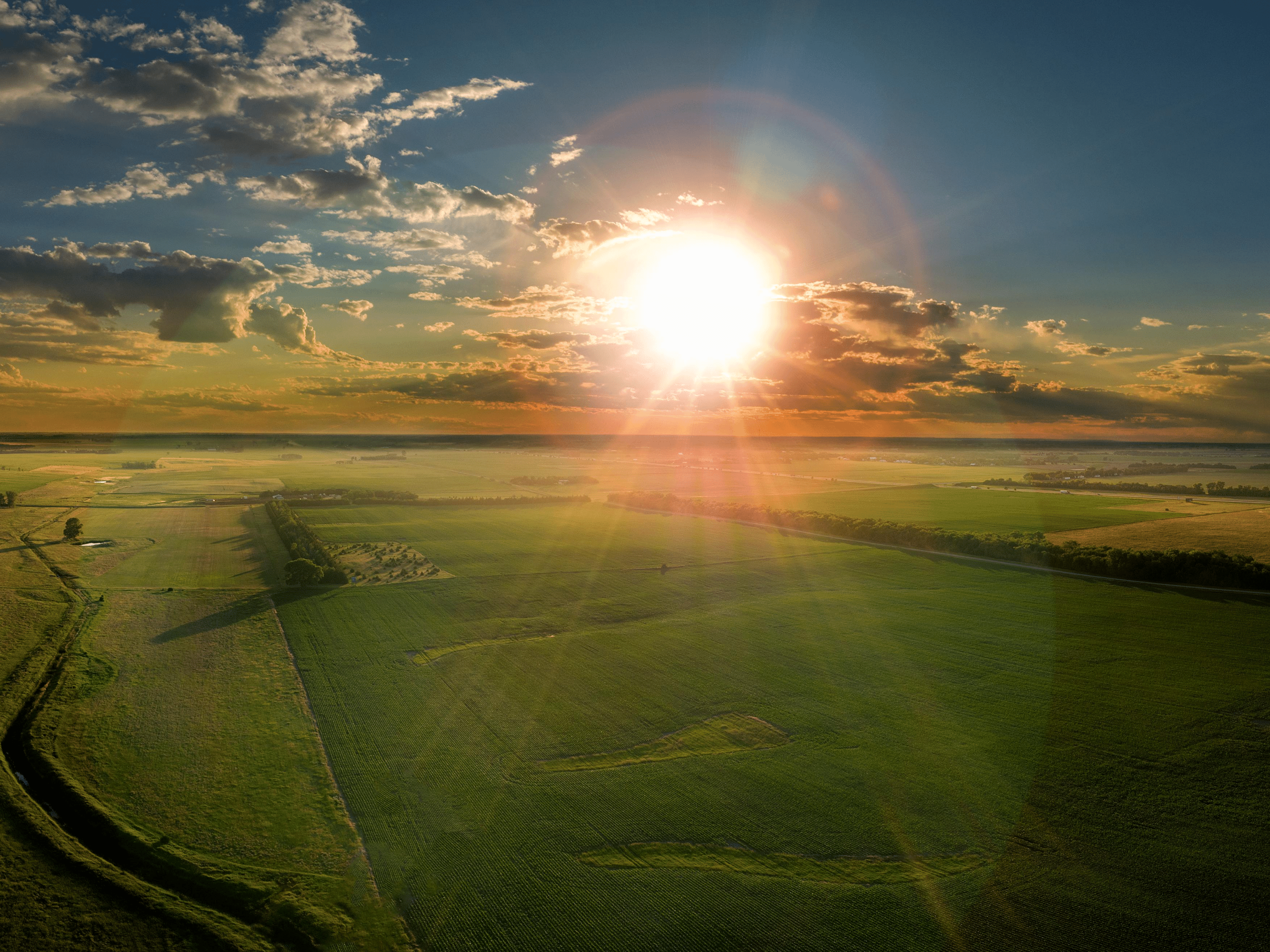 aerial view of sunset over field with clouds in sky