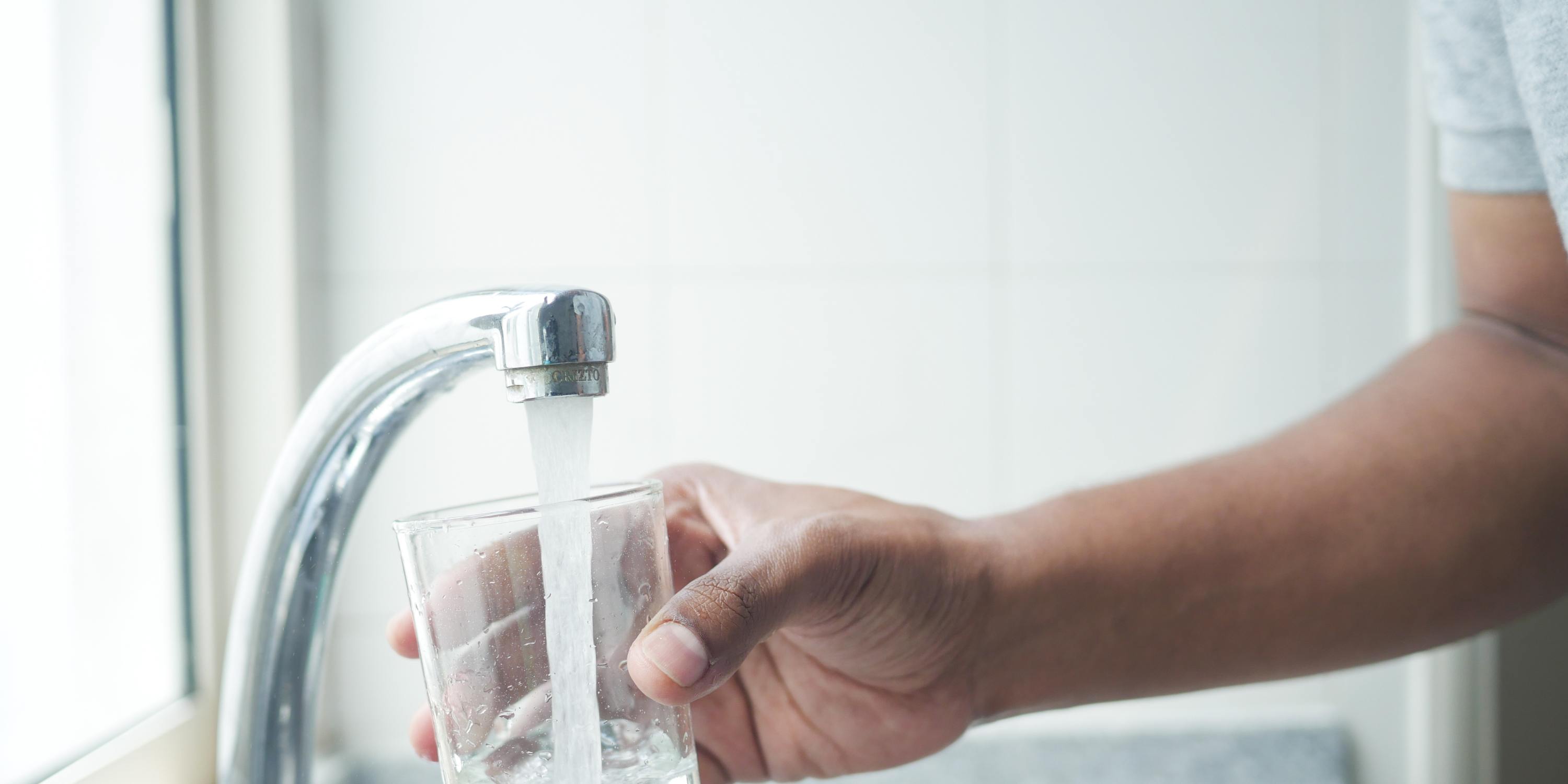 a glass of water is being poured into from faucet