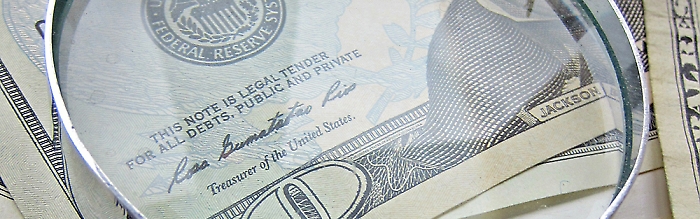 Closeup shot of a ten dollar bill with a magnifying glass on top of it. 