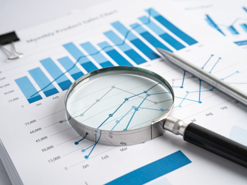 photo of magnifying glass on financial projections and charts
