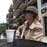 Dr. Castro in a trenchcoat and cap with a coffee cup, cartooned