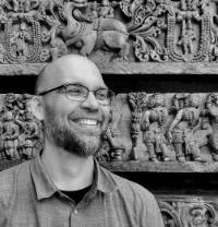 Photo of Dr. Matteson laughing with carved wall behind him