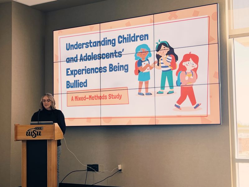 A student presents their research titled "Understanding Children and Adolescents' Experiences Being Bullied".