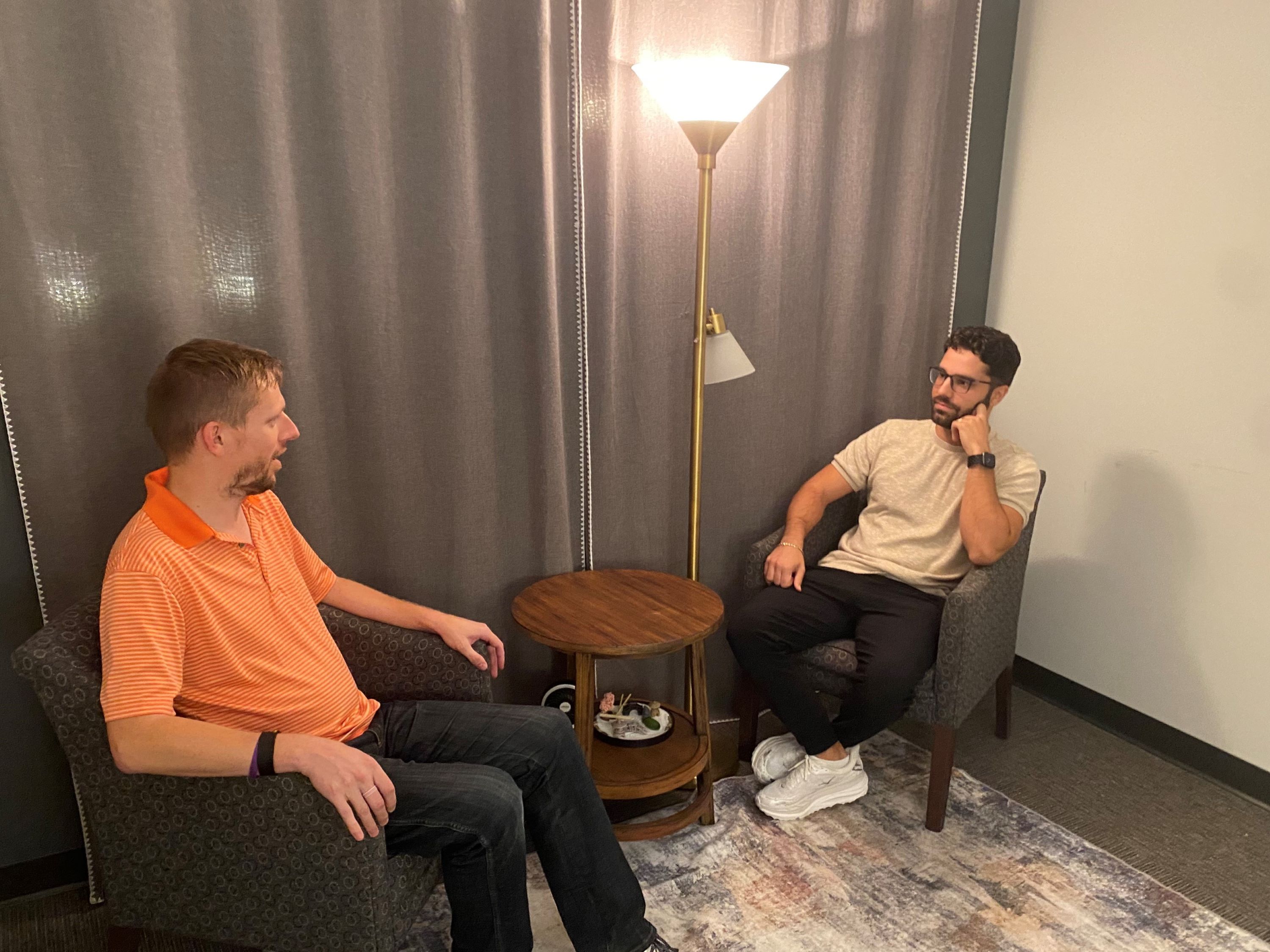 Two men sit in armchairs for a therapy session.