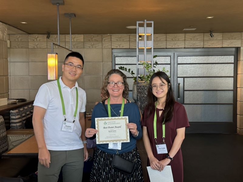 Dr. Carryl Baldwin and two students smile while holding a "Best Poster Award", presented by the Human Factors and Ergonomics Society.