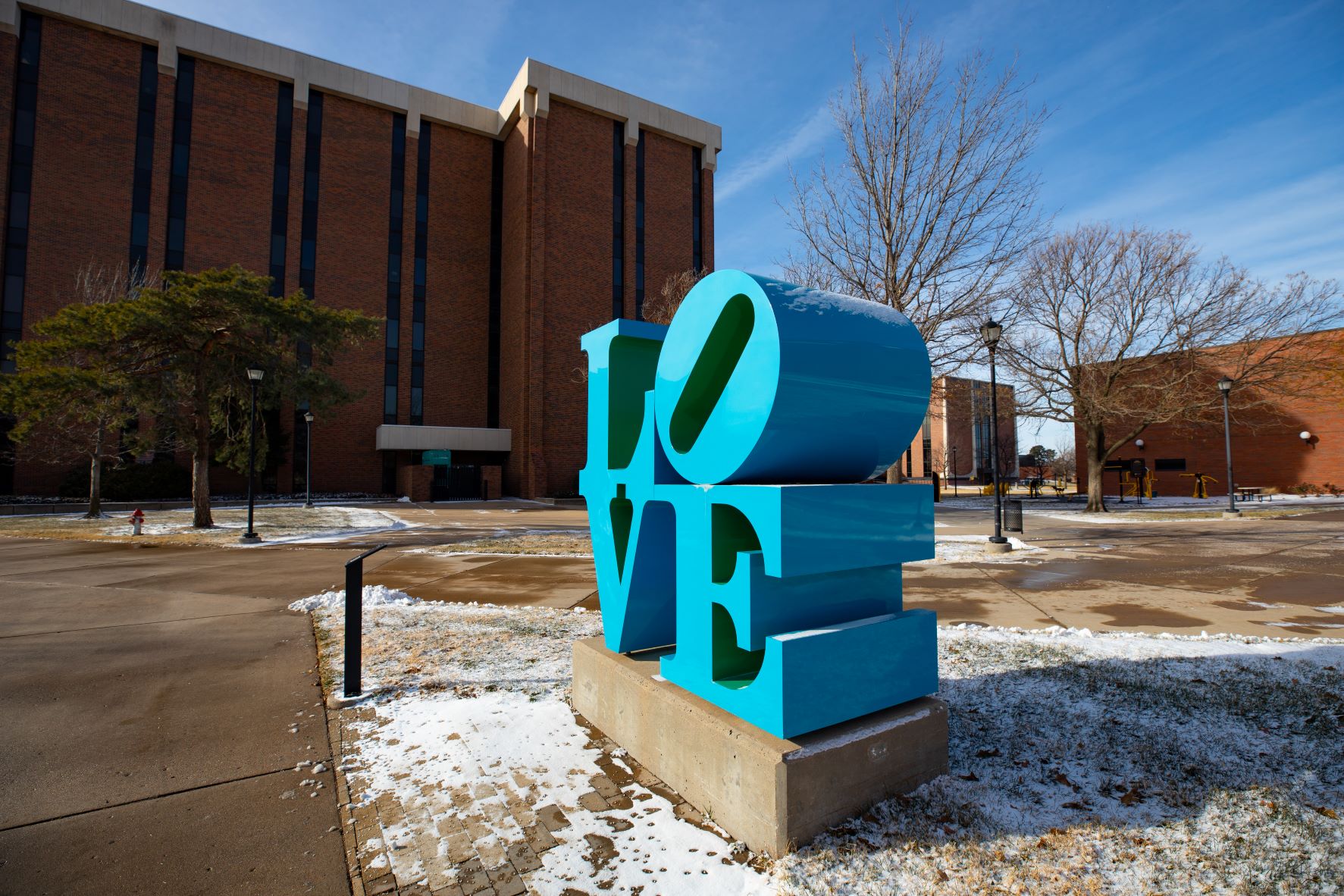 "LOVE" statue with snow on the ground, with Lindquist Hall in the background