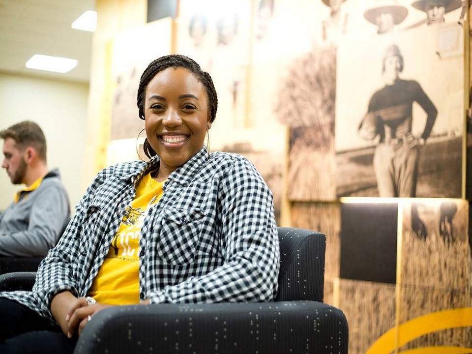 Student sitting in chair, smiling at camera