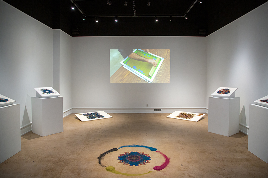 gallery view with drawings made of dust and a video projection on the wall