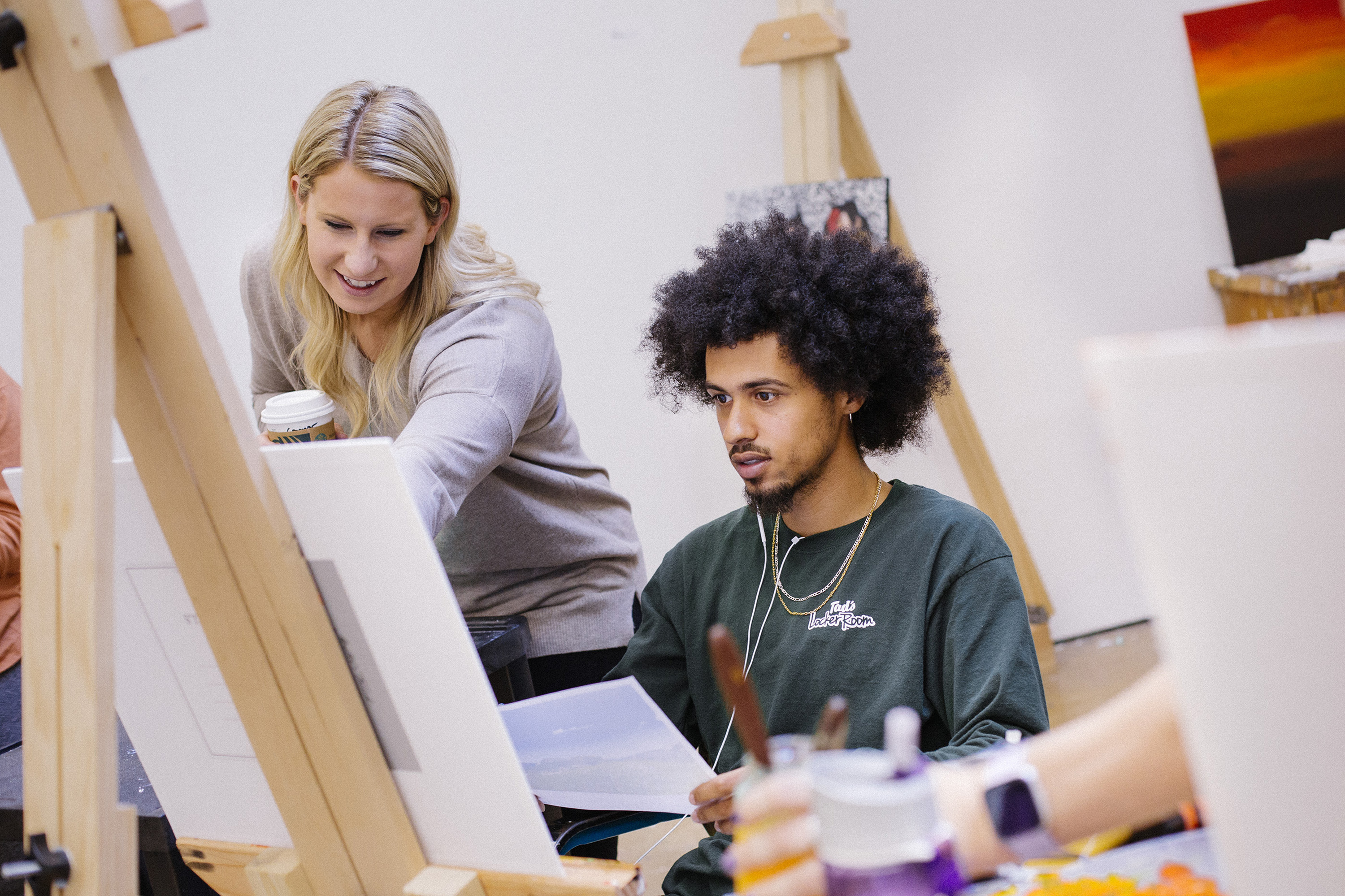 A group of students watch an instructor during a paint media studio class. 