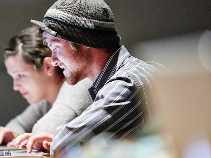 Two students collaborate on a project using a laptop.