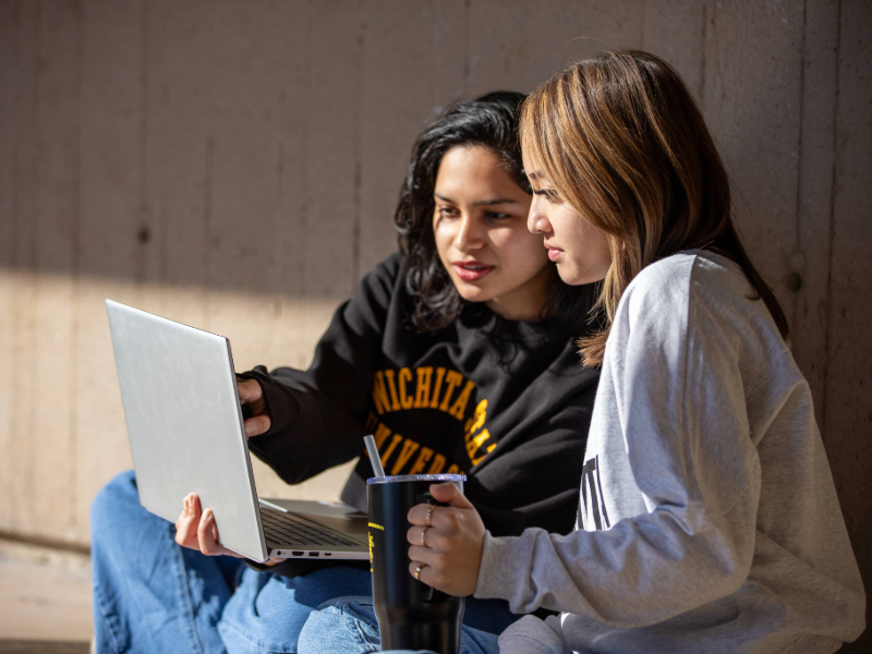 Students in Shocker gear with laptop