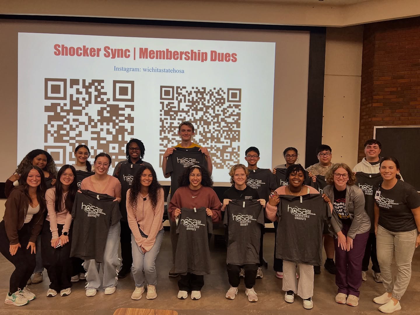 Members of HOSA take a group photo holding HOSA t-shirts