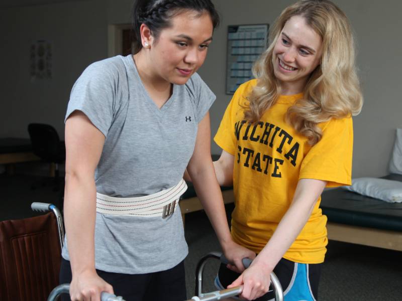 PT Student helping a patient walk with a walker