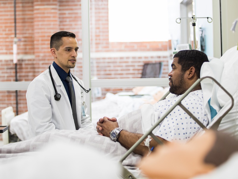 Physician Associate talking with a patient in a hospital bed