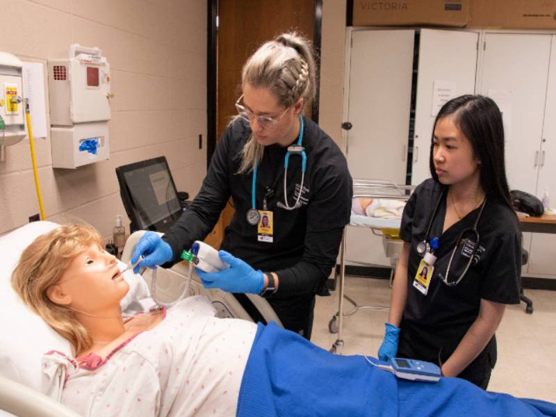 Nursing students taking the temperature of a simulation manequin